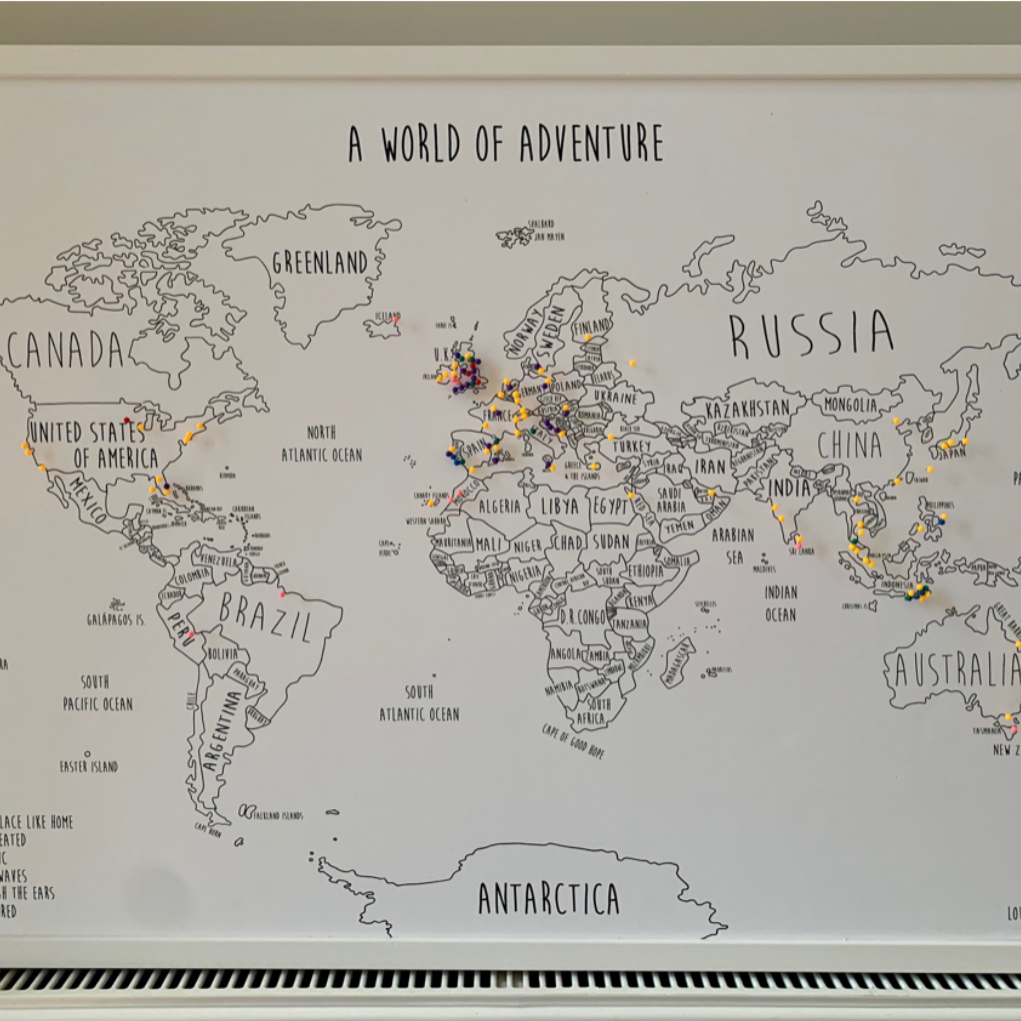 Personalised world pinboard map displayed in a customer’s home with coloured travel pins